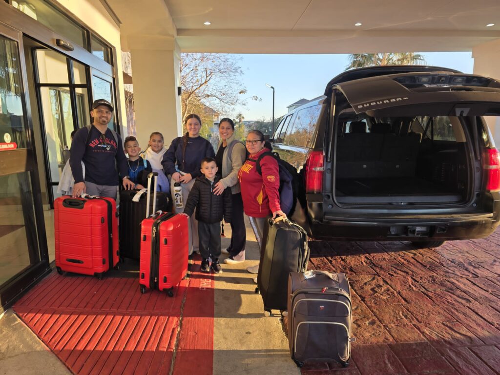 Large family with luggage standing next to black SUV for IAH Airport to Galveston shuttle